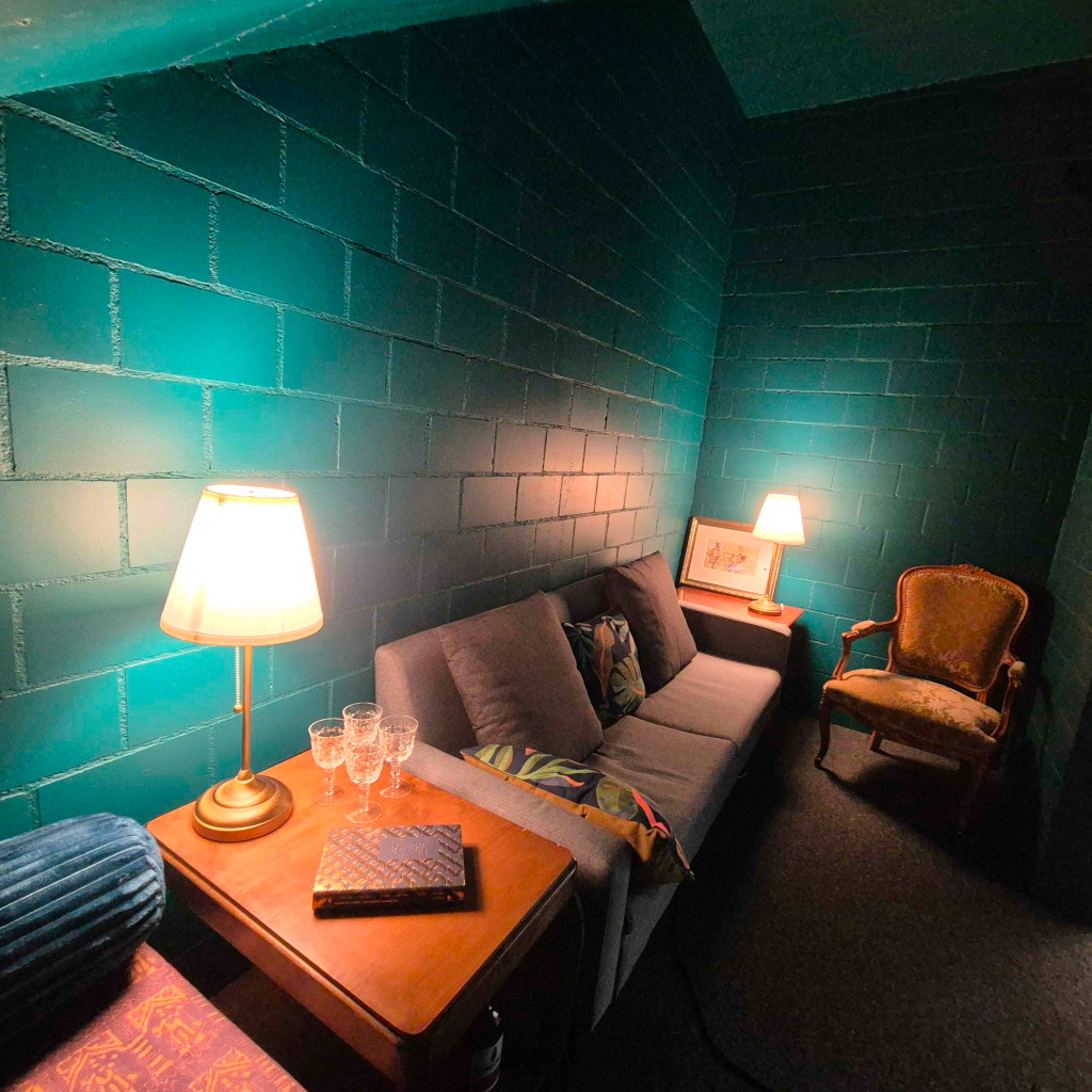 A photograph of a small room with green walls and comfy furniture.